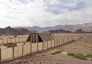 Abri en tissu et clôture dans un environnement aride avec des montagnes en arrière-plan