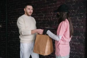 Homme et femme devant un mur de briques échangent un sac brun