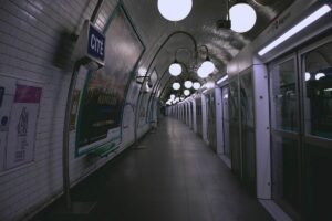Couloir souterrain de station de métro parisien désert, illuminé par des lampadaires, panneaux publicitaires sur les murs