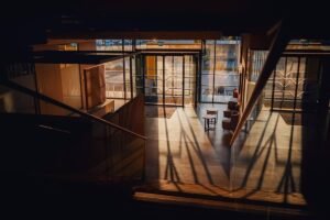 Intérieur d'un espace avec escaliers, fenêtres et meubles, éclairé par la lumière naturelle