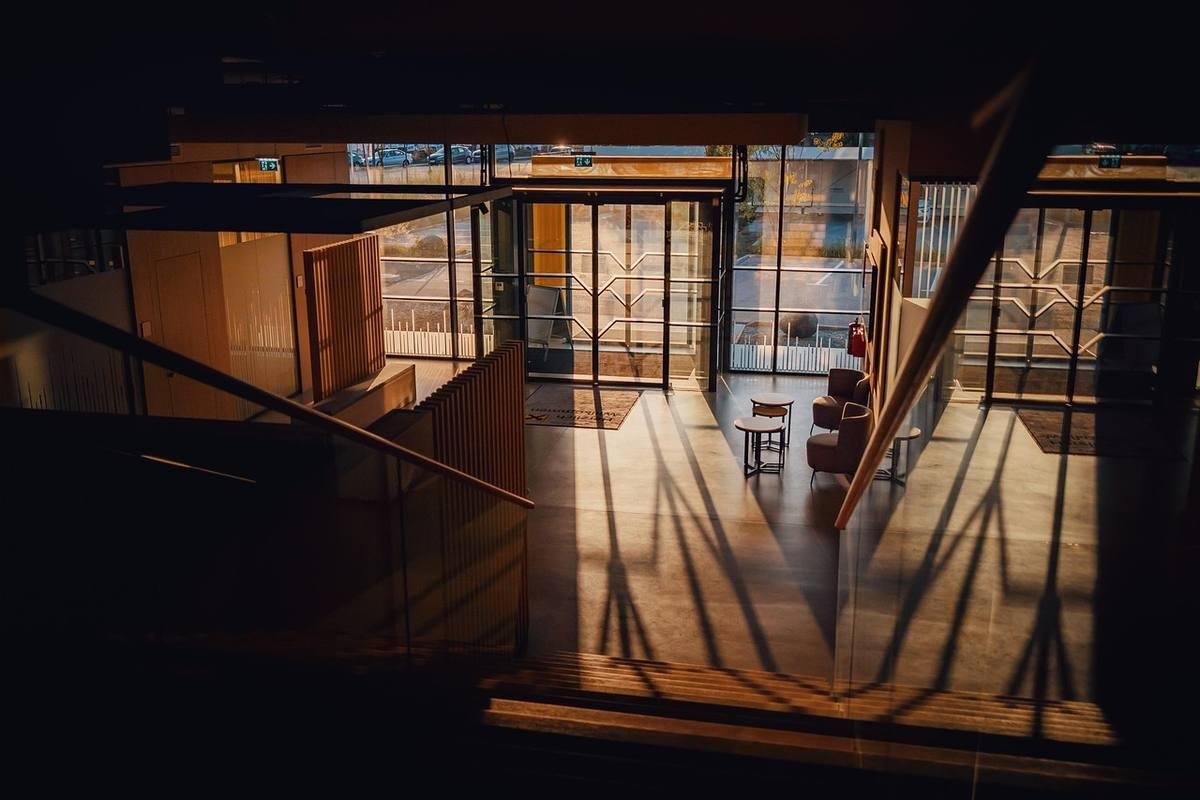 Intérieur d'un espace avec escaliers, fenêtres et meubles, éclairé par la lumière naturelle