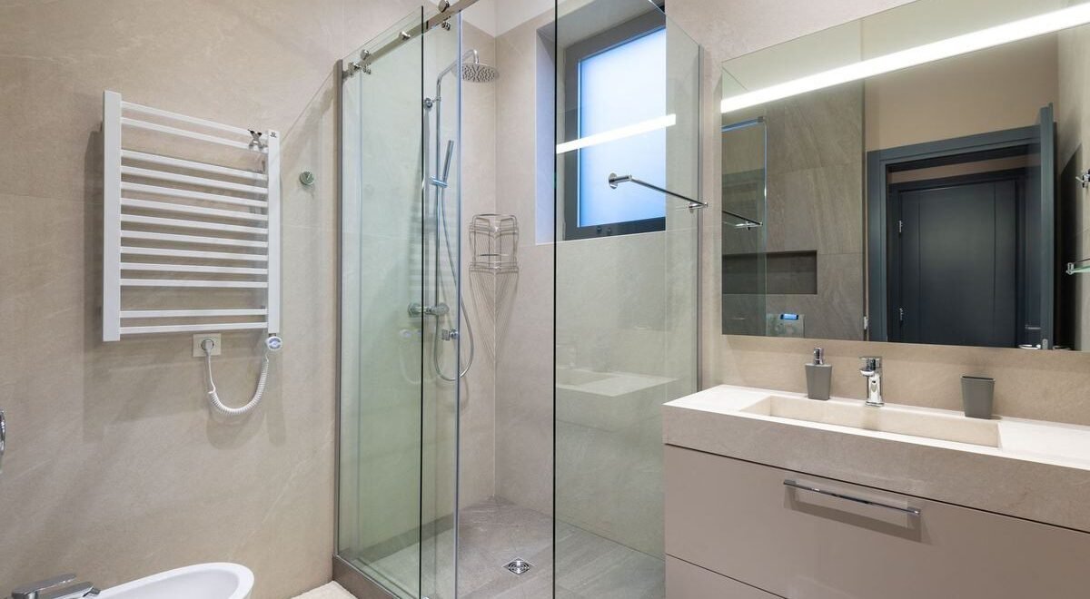 Vue d'une salle de bain moderne avec douche vitrée, vasque et miroir lumineux
