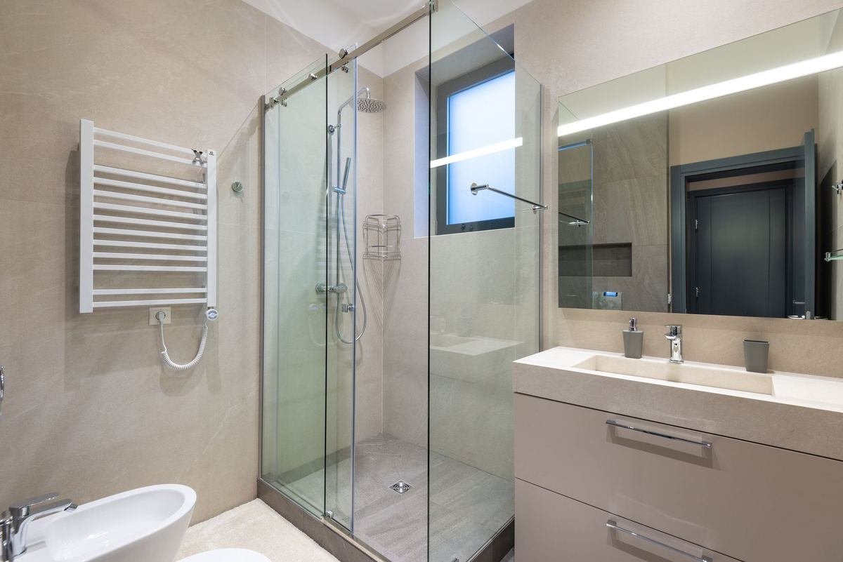 Vue d'une salle de bain moderne avec douche vitrée, vasque et miroir lumineux