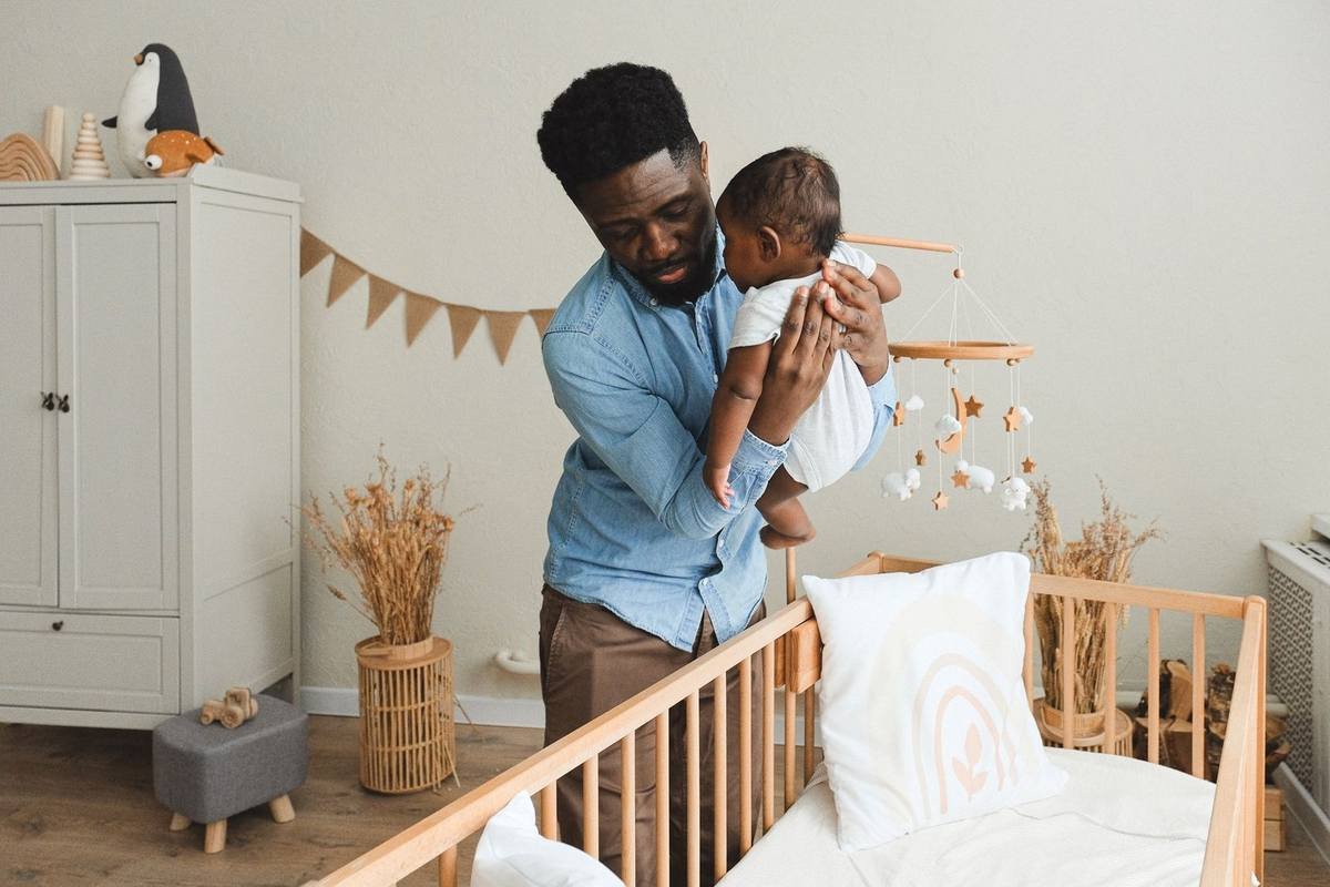 Homme noir portant bébé dans une chambre d'enfant décorée