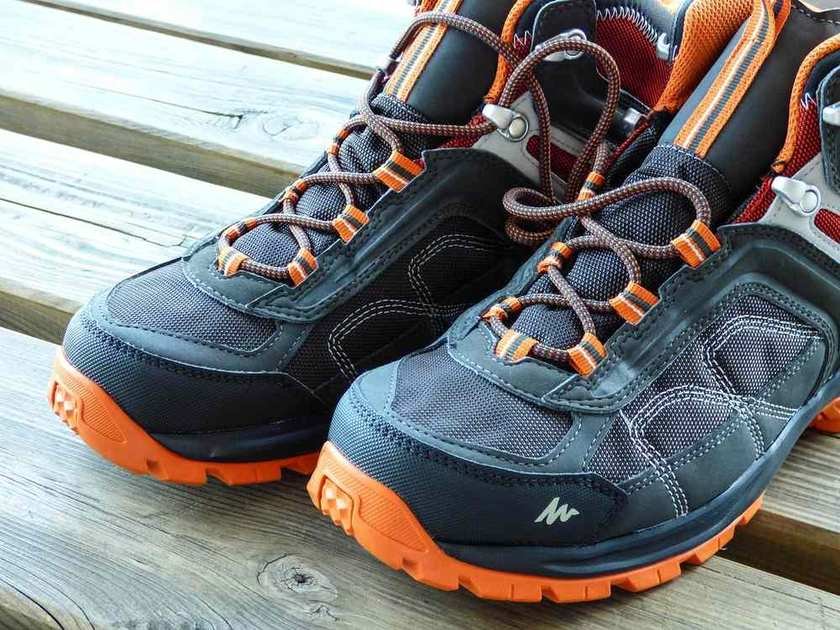 Paire de chaussures de randonnée avec lacets orange posée sur une surface en bois Paire de chaussures de randonnée avec lacets orange posée sur une surface en bois