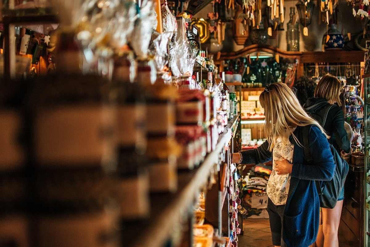 Femme blonde en robe bleue examine des produits sur des étagères dans une boutique décorée