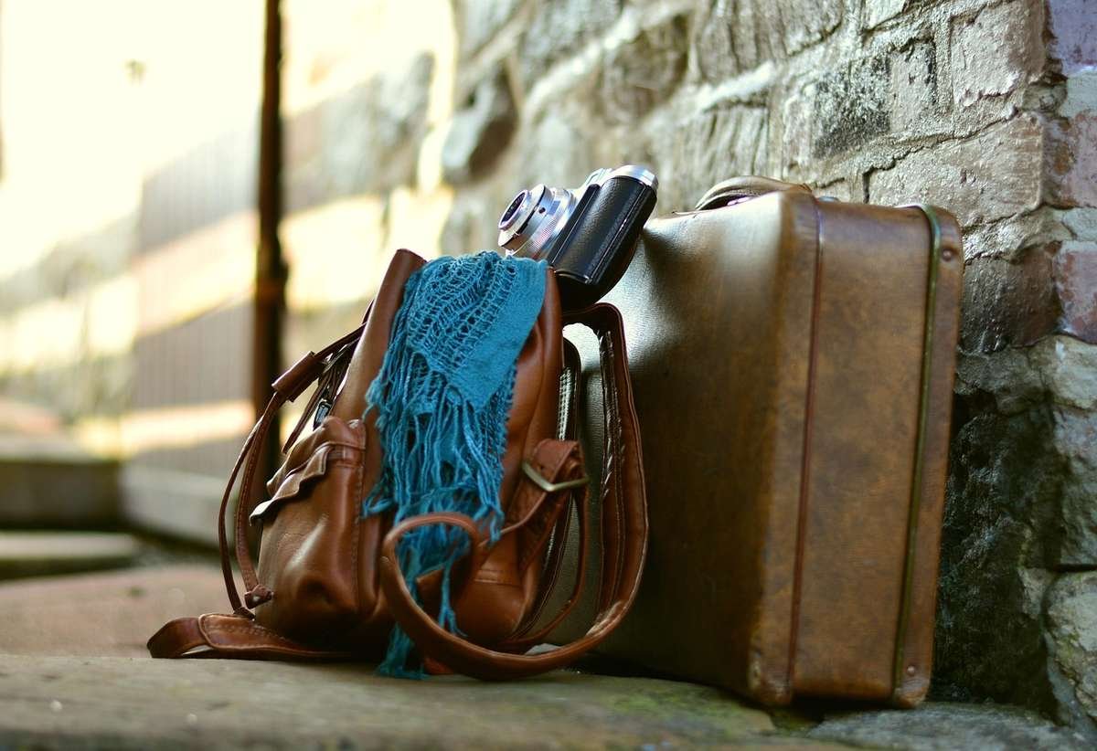 Sac à main, valise, appareil photo et écharpe contre mur de pierre Sac à main, valise, appareil photo et écharpe contre mur de pierre