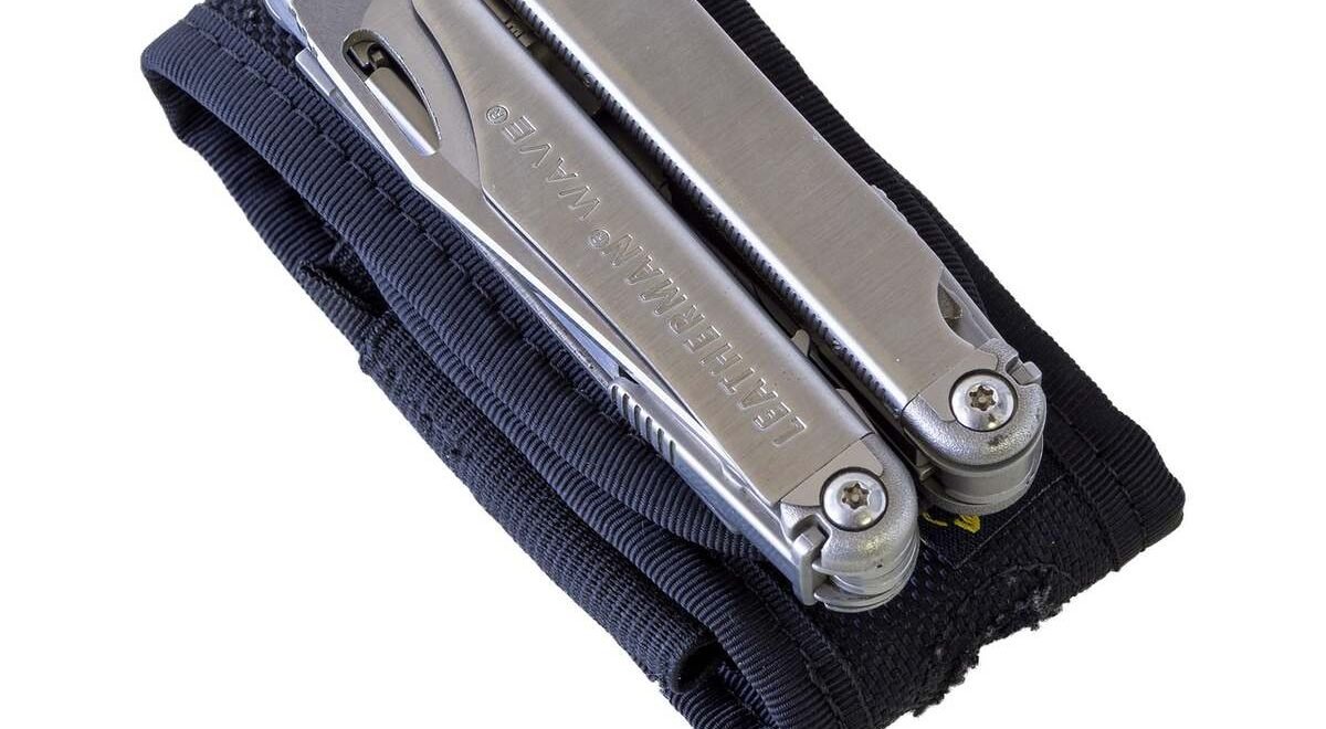 Un multitool métallique glissé dans un sac noir sur fond blanc
