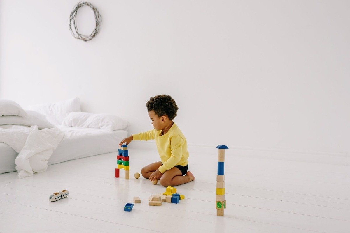 Enfant en jaune jouant avec des blocs de construction sur le sol d'une chambre