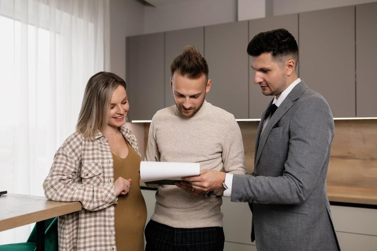 Trois individus dans une cuisine, deux hommes et une femme, consultent un document ensemble Trois individus dans une cuisine, deux hommes et une femme, consultent un document ensemble