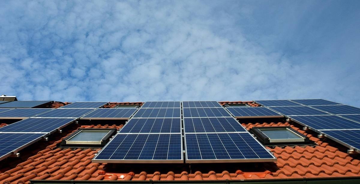 Panneaux photovoltaïques sur toit rouge avec ciel nuageux
