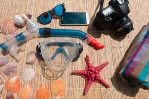 Équipement de plongée, coquillages, étoile de mer, téléphone, appareil photo, serviette sur tapis de paille