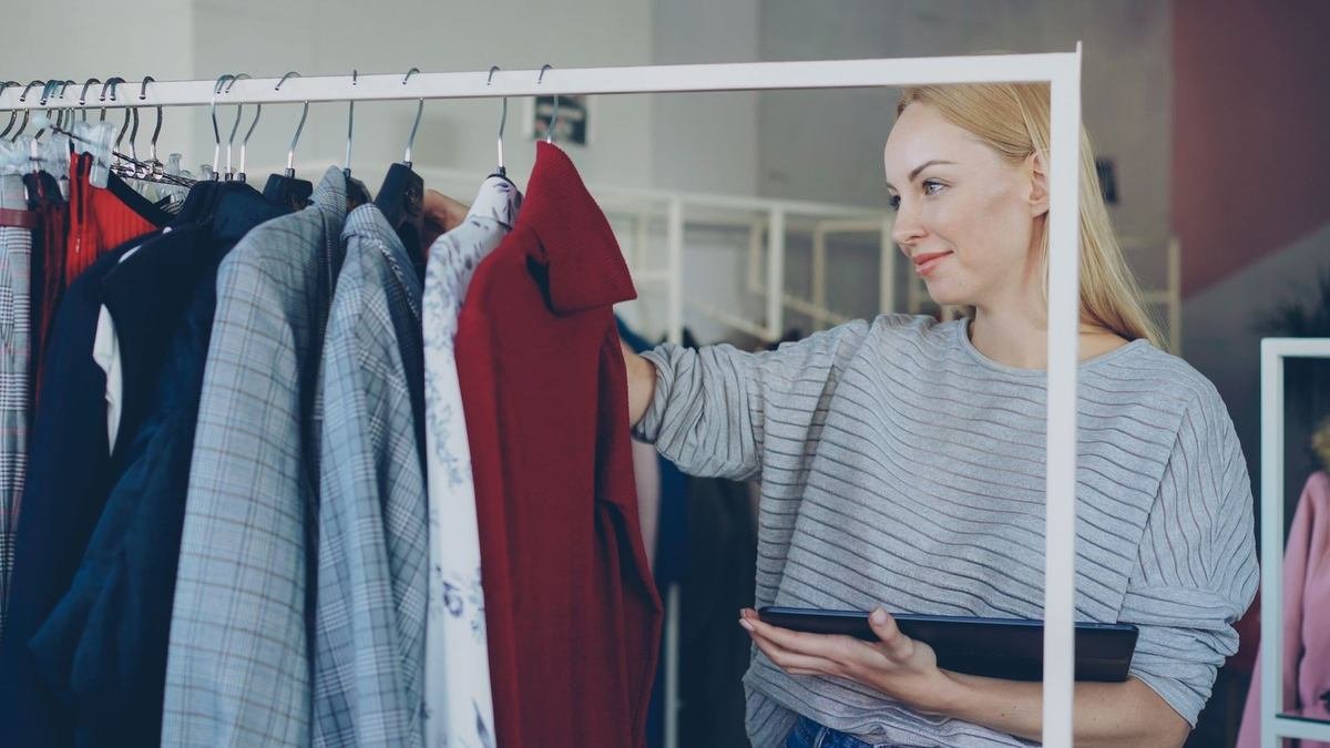 Femme inspecte des articles de mode sur une étagère dans un magasin