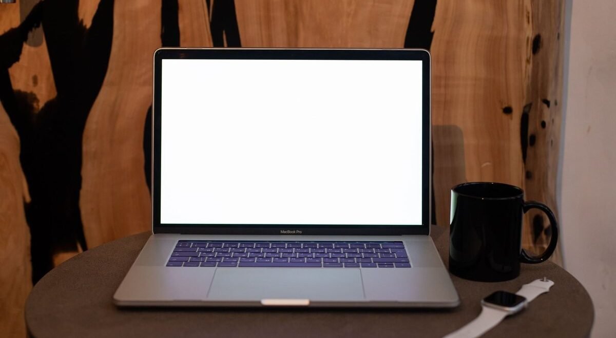 Un ordinateur portable ouvert sur une table avec une tasse et une montre