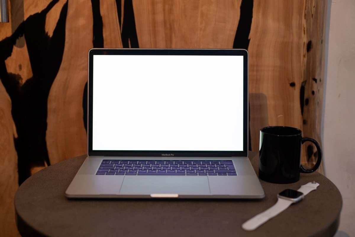 Un ordinateur portable ouvert sur une table avec une tasse et une montre