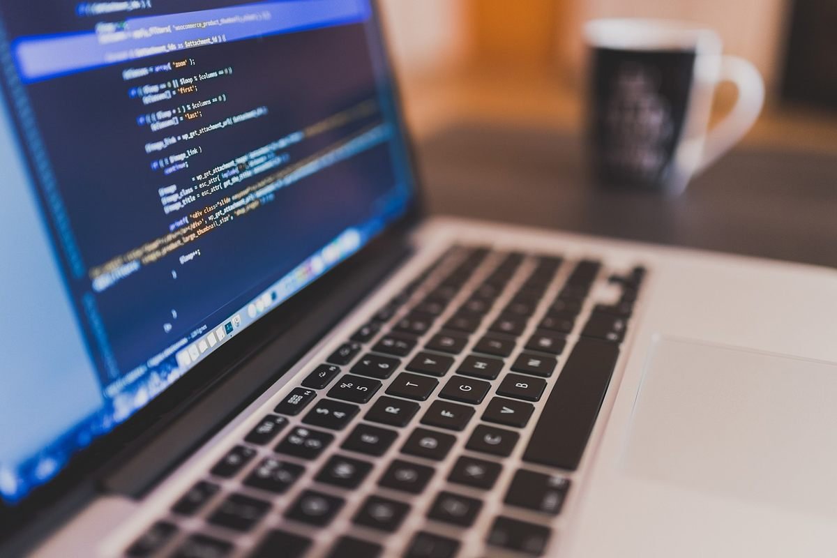 Un ordinateur portable affiche du code sur son écran tasse à côté